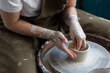 Woman doing pottery on the potter wheel on the workshop