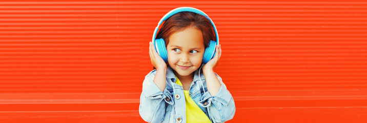 Portrait of happy smiling child in headphones listening to music on city street