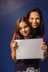 Mãe e filha abraçadas com cartaz em branco para reclame.