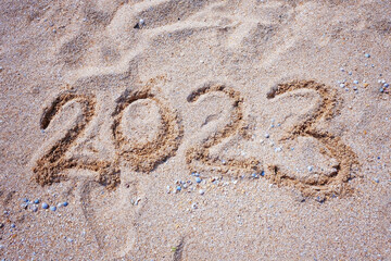 New Year 2023. Figures on the sandy shell seashore.