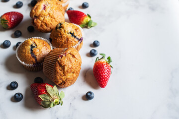 Blueberry and strawberry muffins with berries on a marble background. Close up and copy space. - 535918905