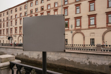 Obraz premium Gray colored blank signage mounted on pole at city street against building background