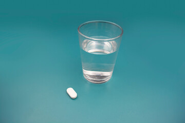 Pill and glass of water on blue background