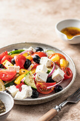Traditional greek salad with feta cheese, tomatoes, red onion, cucumber, pepper, olive oil and italian herbs served on brown background with rustic fork