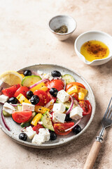 Fototapeta na wymiar Traditional greek salad with feta cheese, tomatoes, red onion, cucumber, pepper, olive oil and italian herbs served on brown background with rustic fork