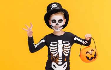 Happy cheerful boy in skeleton costume with  pumpkin  basket celebrates Halloween and scary gesture...