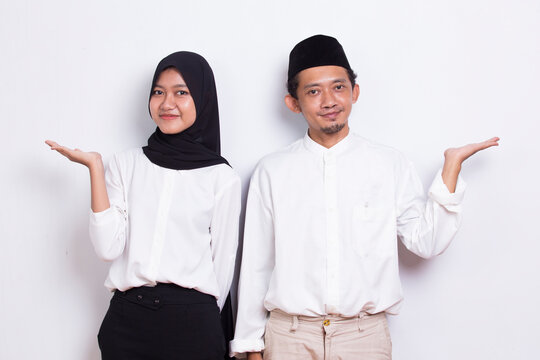 young asian muslim couple pointing with fingers to different directions isolated on white background