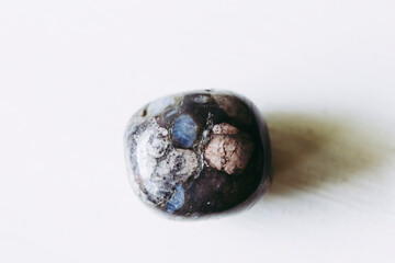 Galet pierre roulée polie glaucophane sur un fond blanc avec espace vide - Minéral naturel