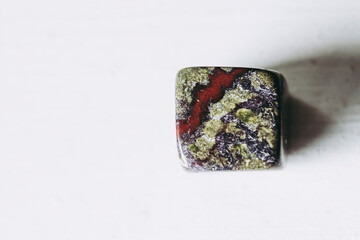 Galet pierre roulée polie jaspe sang de Dragon sur un fond blanc avec espace vide - Minéral naturel