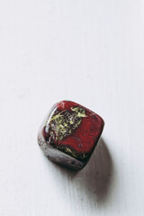 Galet pierre roulée polie jaspe sang de Dragon sur un fond blanc avec espace vide - Minéral naturel