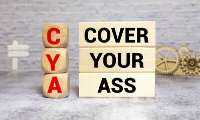text CYA cover your ass on wooden block