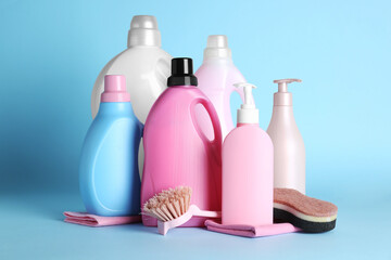 Different cleaning supplies and tools on light blue background