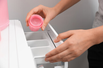 Woman pouring laundry detergent into drawer of washing machine, closeup