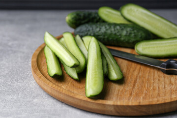 Whole and cut fresh ripe cucumbers on grey table