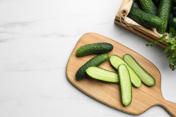 Fresh ripe cucumbers and parsley on white marble table, flat lay. Space for text