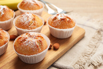 Tasty muffins powdered with sugar on table, closeup