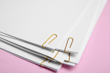 Sheets of paper with clips on pink background, closeup