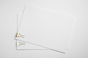 Sheets of paper with clips on white background, top view