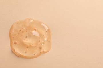 Sample of face gel on pale orange background, top view. Space for text