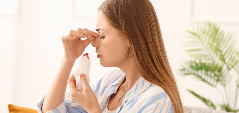 Young Woman With Nosebleed At Home