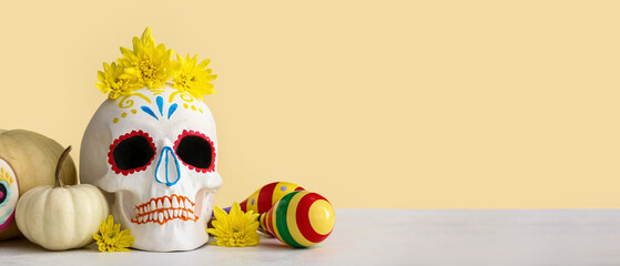 Painted human skull with flowers, pumpkins and maracas on color background with space for text. El Dia de Muertos