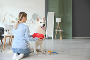 Woman with her white dog and first aid kit at home