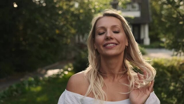 A beautiful caucasian woman walks looks into the camera and smiles.