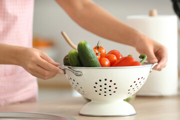 Young woman with fresh vegetables in kitchen, closeup