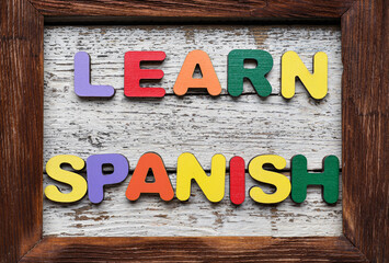 Text LEARN SPANISH and frame on white wooden background