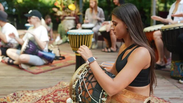 A young beautiful woman plays a hand drum