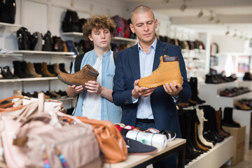 Man visiting shoe shop with teenage son in search of comfortable spring and autumn shoes .
