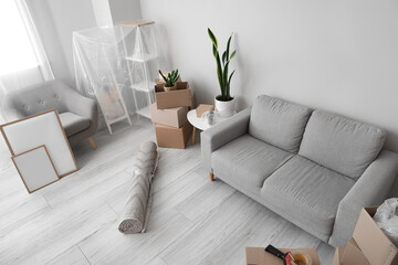 Cardboard boxes with sofa, armchair and frames in living room on moving day