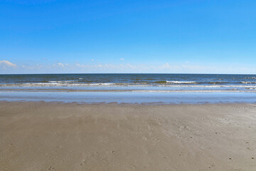 Fototapeta na wymiar deserted empty beach with fluffy clouds on the horizon and clear blue sky