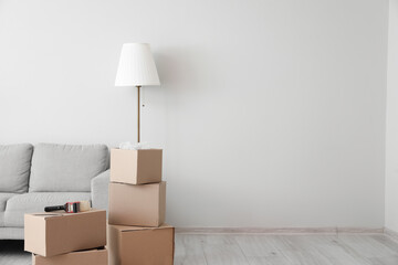 Cardboard boxes with sofa and lamp in living room on moving day