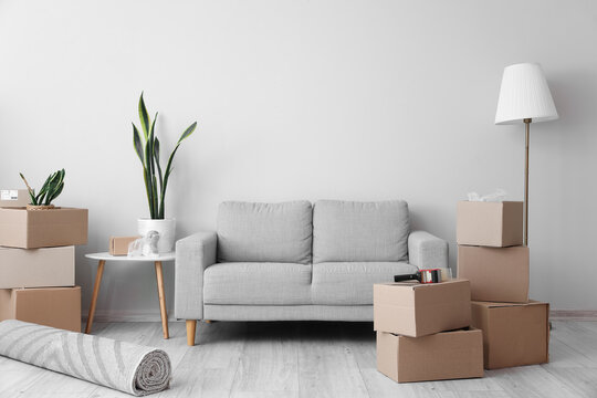 Cardboard boxes with sofa and lamp in living room on moving day