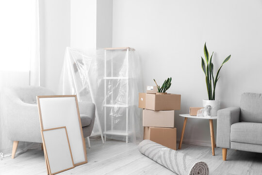 Cardboard boxes with armchair and frames in living room on moving day