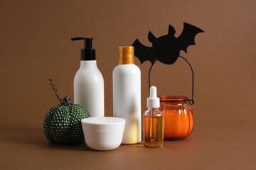 cosmetics products and halloween decor on brown background