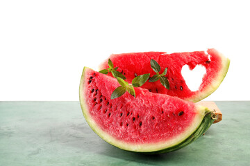 Slices of ripe watermelon with mint on green table against white background