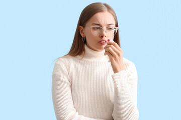 Young woman with nosebleed and tissue on blue background