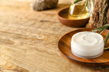 Plate with jar of natural olive cream on wooden table