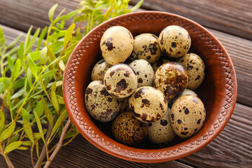 Bowl with fresh quail eggs on wooden background, closeup