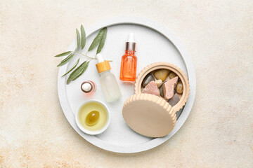 Board with bottles of essential olive oil on light background