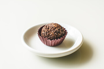 Brigadeiro, traditional brazilian sweet, on a plate, white background.