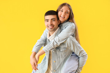 Fashionable young couple in autumn clothes on yellow background