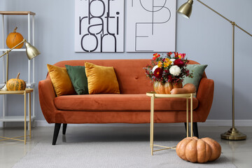 Interior of modern living room with autumn flowers in pumpkin and sofa