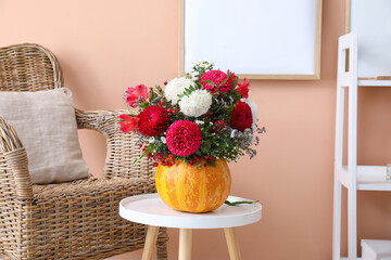 Pumpkin with autumn flowers on table in living room