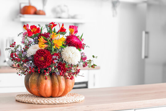 Pumpkin with autumn flowers on counter in kitchen