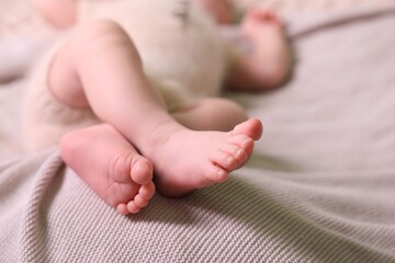 Cute newborn baby lying on light grey knitted plaid, closeup. Space for text