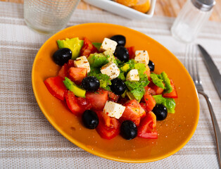 Portion of fresh avocado salad with feta cheese, tomatoes and black olives.