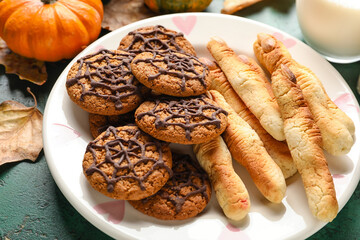 Plate with Halloween cookies on grunge background, closeup